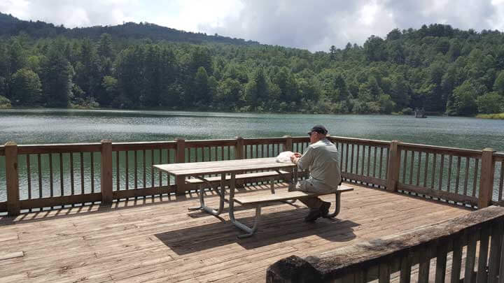 גבר יושב לפני שולחן בשפת אגם